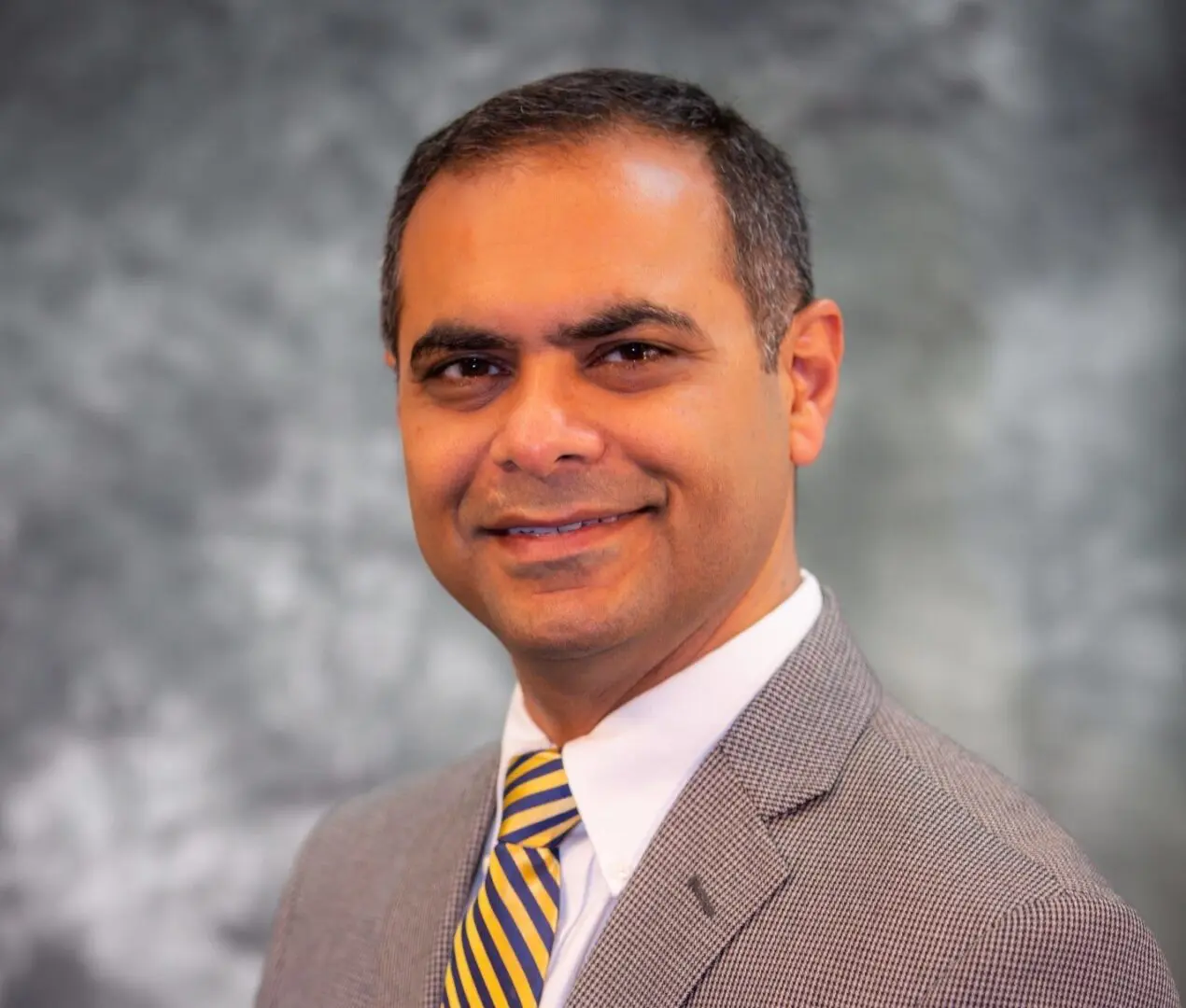 A man in a suit and tie smiling for the camera.